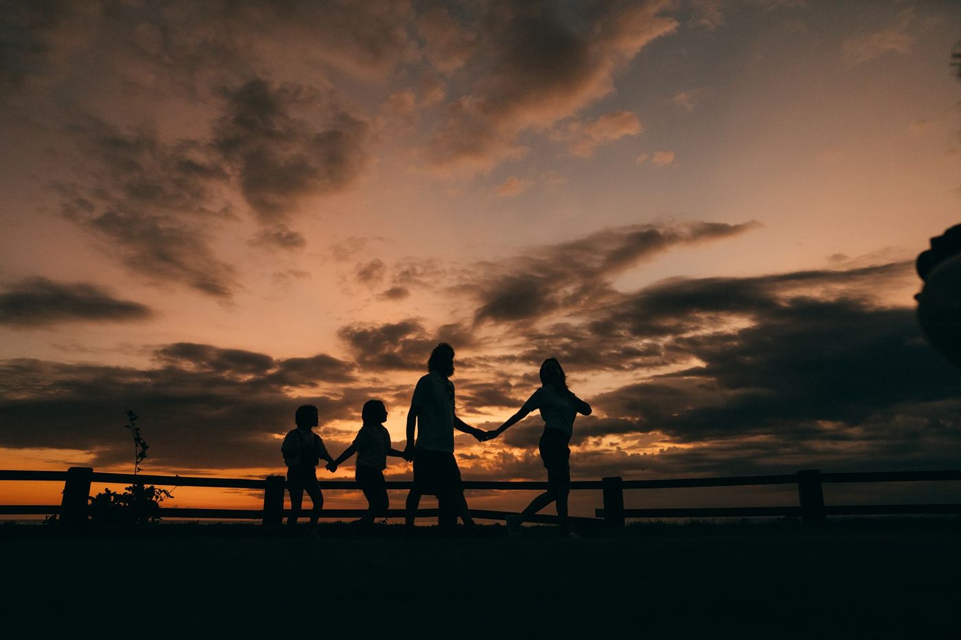 Silhueta de uma família caminhando de mãos dadas ao entardecer